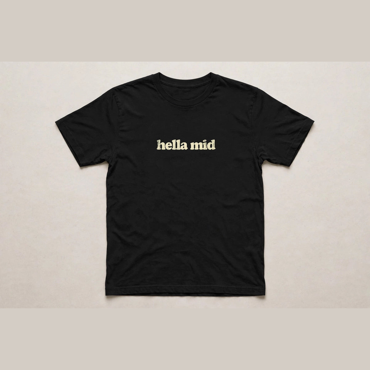 Hella Mid funny slang t-shirt in Black - distressed cream lowercase text, Bella Canvas tee, flat lay front view, funny gen z humor shirt