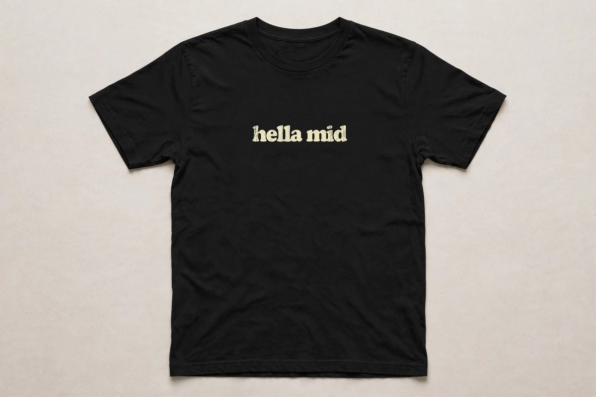 Hella Mid funny slang t-shirt in Black - distressed cream lowercase text, Bella Canvas tee, flat lay front view, funny gen z humor shirt