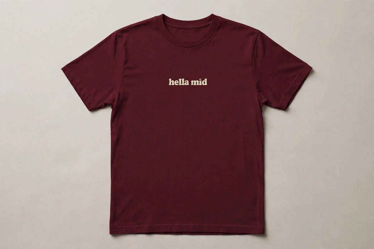 Hella Mid funny slang t-shirt in Maroon - distressed cream lowercase text, Bella Canvas tee, flat lay front view, funny gen z humor shirt