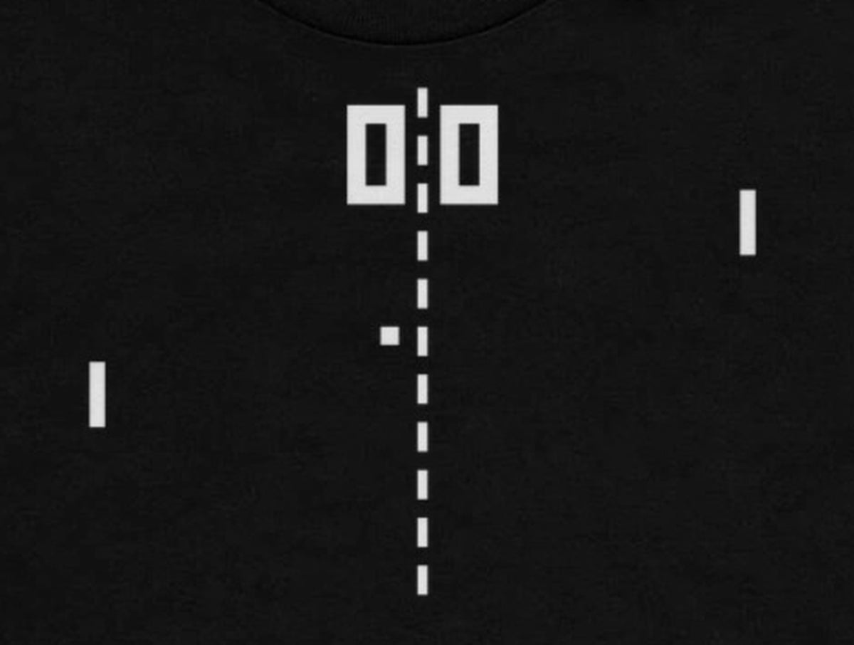 Pong shirt design close-up - blocky 0-0 score digits, dashed center net and square ball print detail