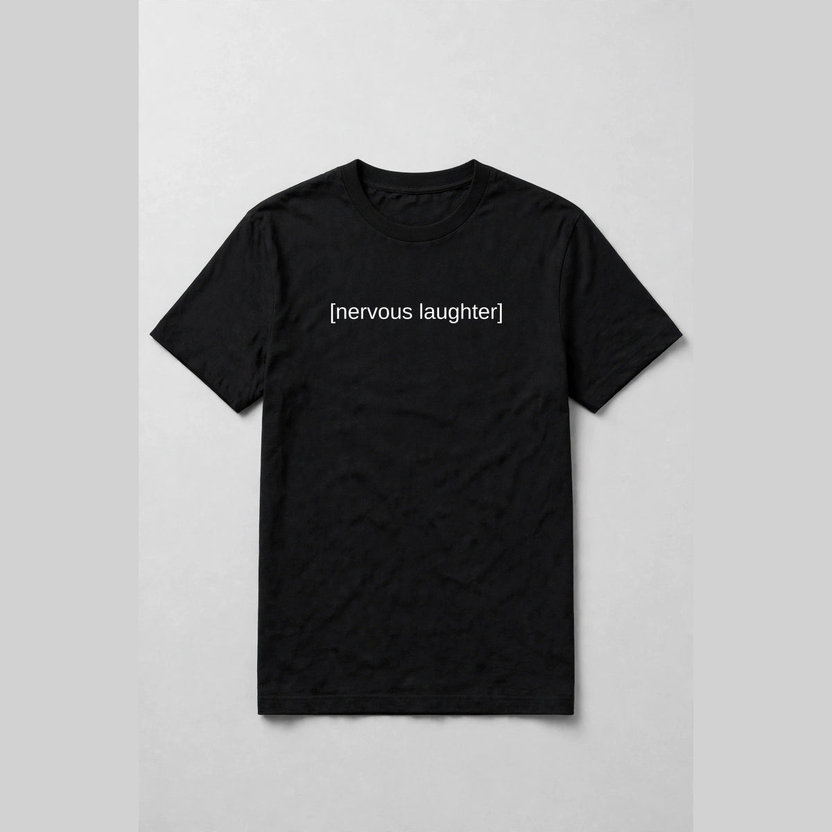 Black t-shirt with white subtitle text [nervous laughter] across the chest like a movie caption